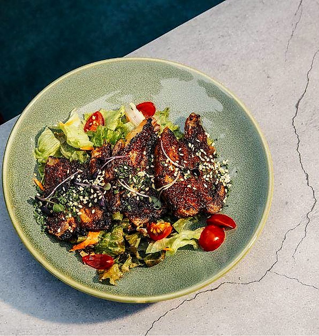 A glazed meat salad with sesame on a green plate